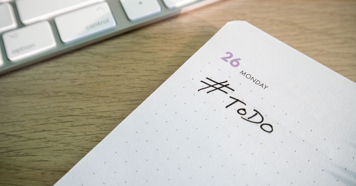 Person looking at an incomplete to-do list lying on a wooden desk