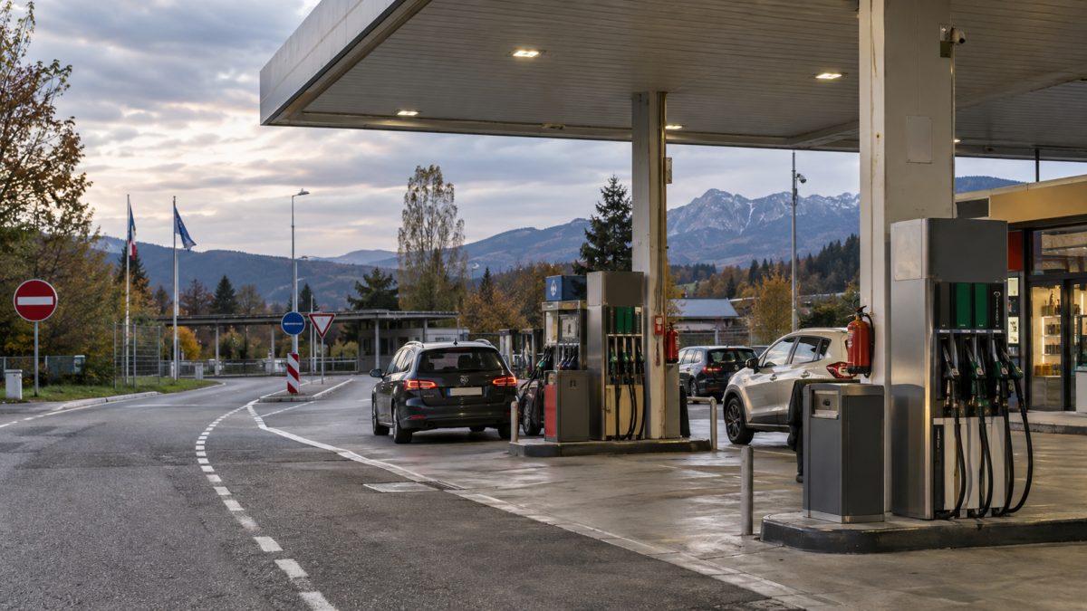 Europeisk bensinstasjon med flere drivstoffpumper og biler i lyset sent på dagen