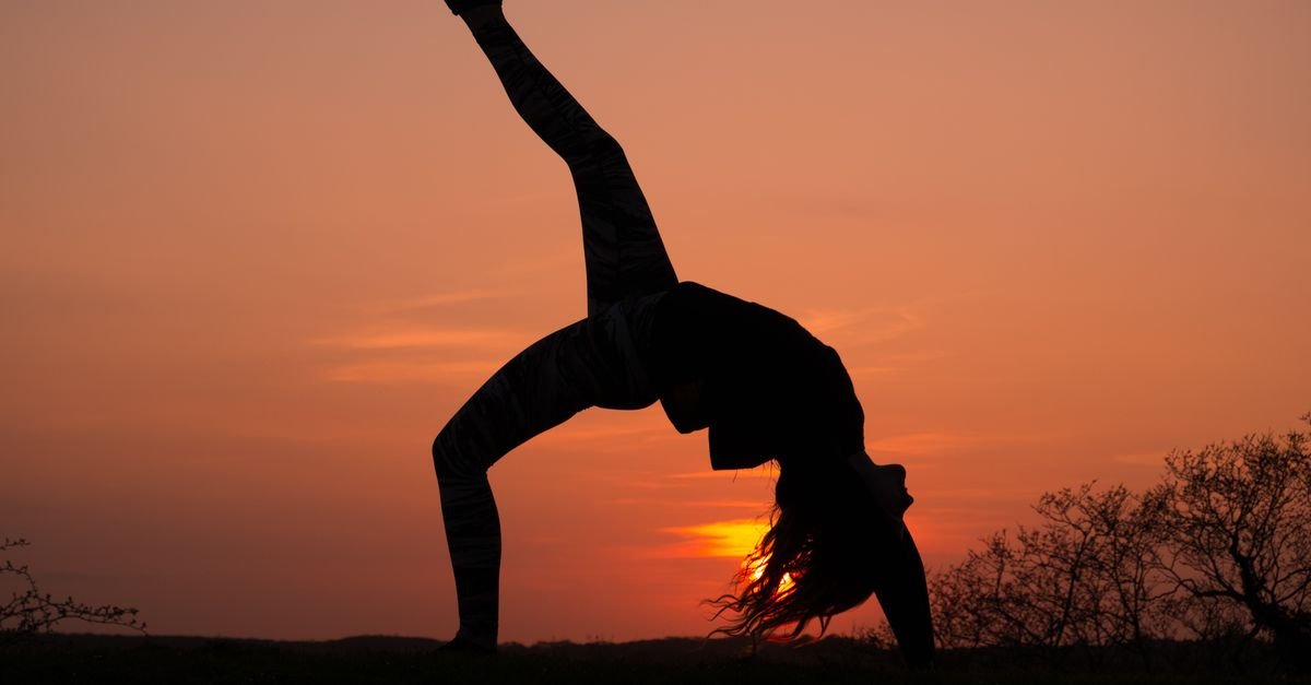 Silhouette of a person balancing on one leg in the golden light of sunset