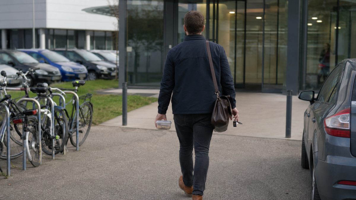 Employee arriving at the office with a bag, transport pass and takeaway meal
