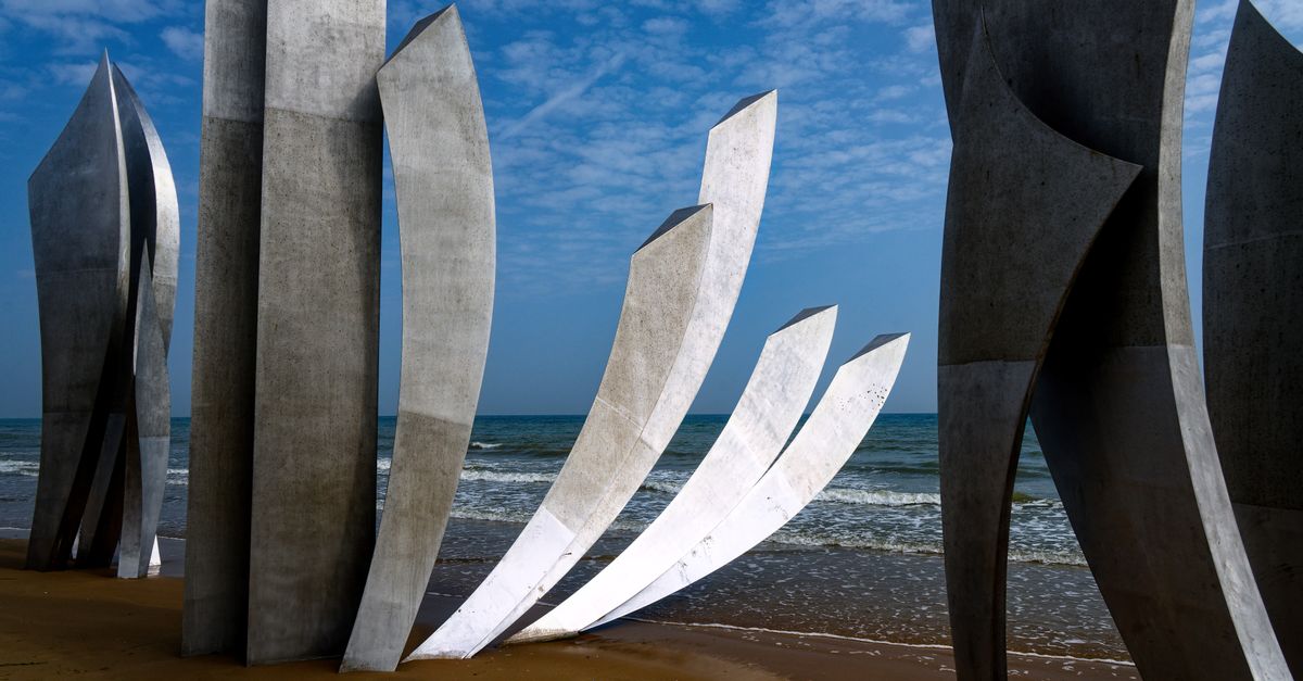 D-Day 2026纪念活动期间，带有登陆纪念碑和旗帜的诺曼底海滩