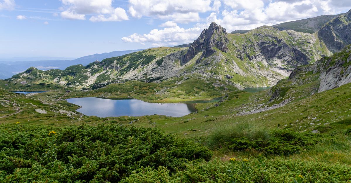 Mountain lake surrounded by green peaks, a cool destination for escaping the summer 2026 heatwave