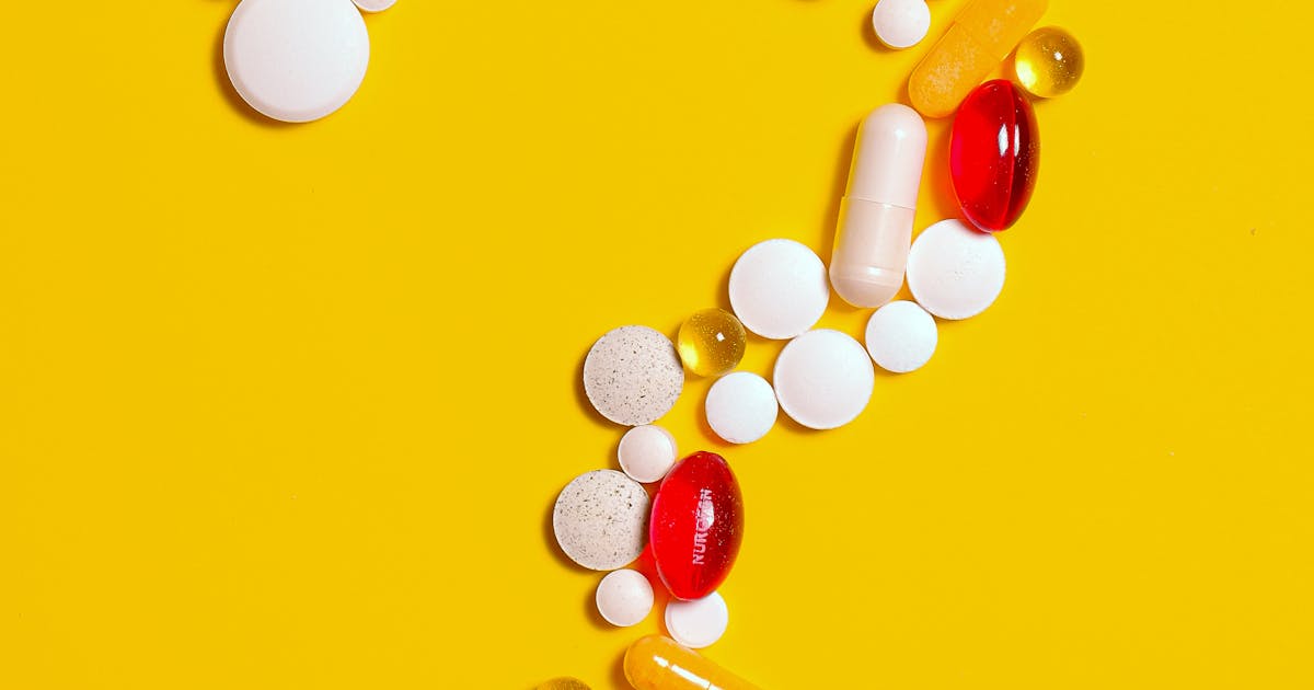 White pill placed on a medical surface with a stethoscope and a heart model in the background
